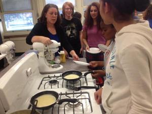 Madame Williams (left) instructs Dave Mundy (10), Isarel Novo (10), Anjanie Gilzean-Colon (9), and Priya Jassal (11) cook crepes.